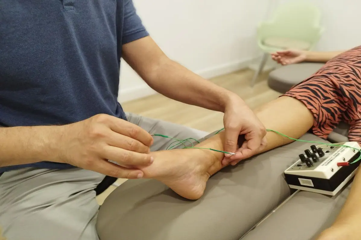Fisioterapeuta de Prosana aplicando electroacupuntura en el tobillo de una paciente